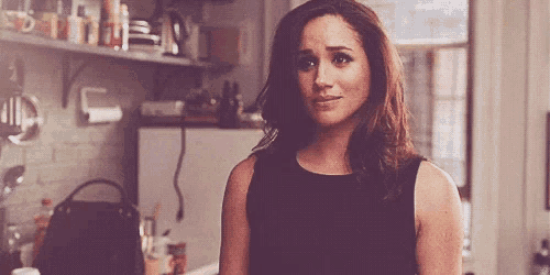 a woman is standing in a kitchen wearing a black tank top .