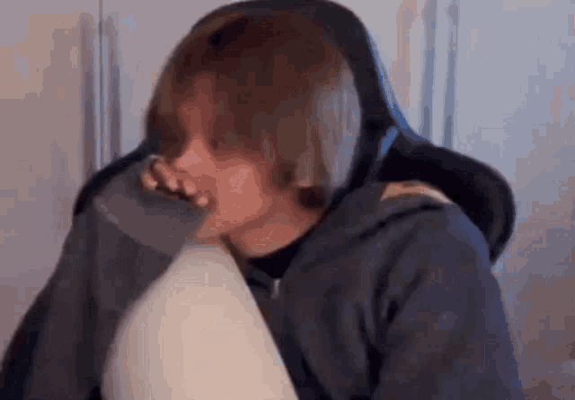 a person is sitting in a chair with a pillow in their lap and a cup in their mouth .