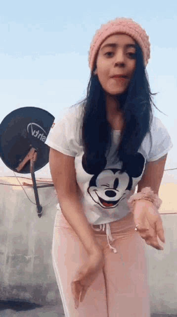 a woman wearing a mickey mouse t-shirt and a pink hat