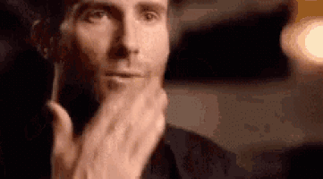 a man is holding his hand to his chin while looking at the camera .