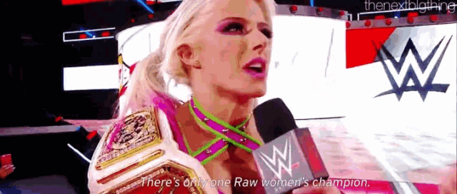 a woman is talking into a microphone while wearing a raw women 's champion belt .
