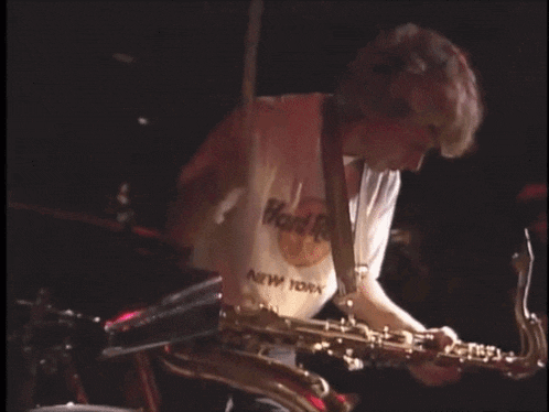 a man playing a saxophone with a hard rock new york shirt on