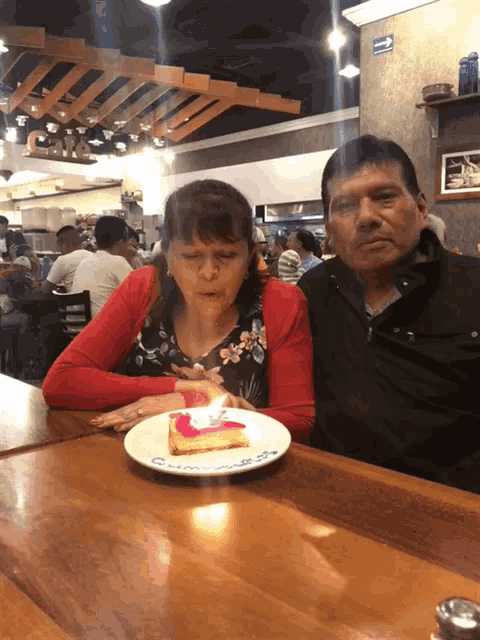 a man and a woman are sitting at a table with a plate of food and a piece of cake