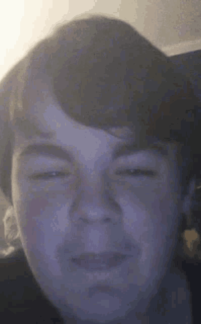 a close up of a boy 's face with his eyes closed and his mouth open