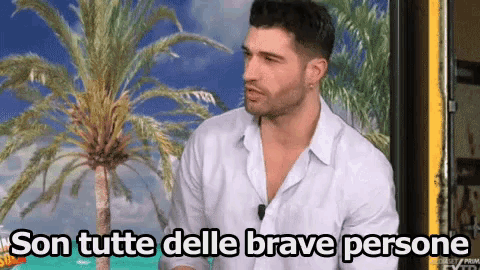 a man in a white shirt is standing in front of a palm tree with the words son tutte delle brave persone above him