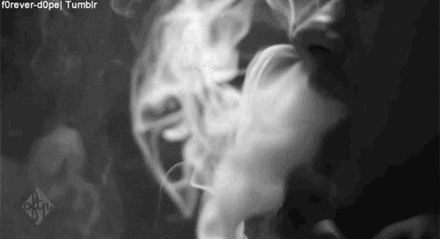 a black and white photo of a person smoking a cigarette with smoke coming out of their mouth .
