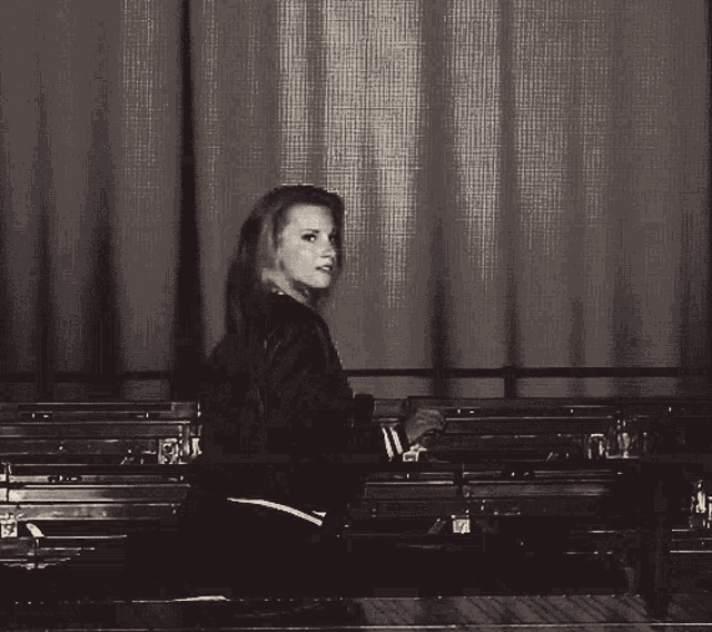 a woman in a black jacket sits in a row of bleachers