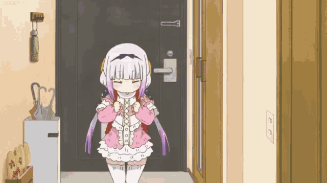 a girl in a pink dress is standing in a hallway with her eyes closed