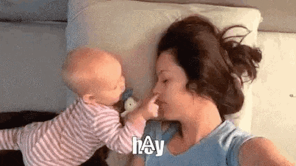 a woman is laying on a bed with a baby on her chest .