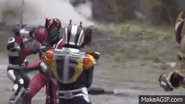 a group of kamen riders are fighting each other in a dirt field .
