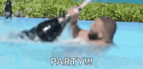 a man is holding a bottle of champagne in a pool .