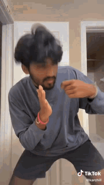 a man in a blue shirt and black shorts is dancing in front of a white door .