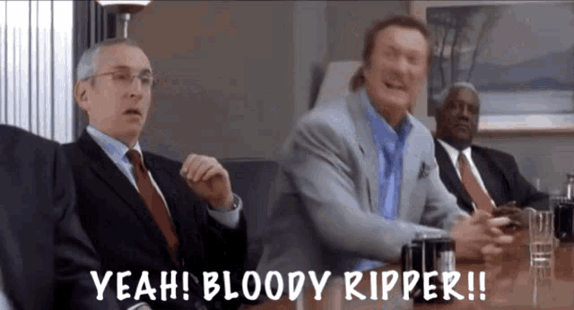 three men in suits and ties are sitting at a table and one of them is saying " bloody ripper "