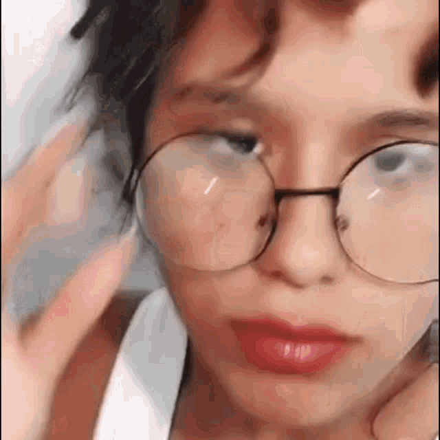 a close up of a person wearing glasses and a white shirt .