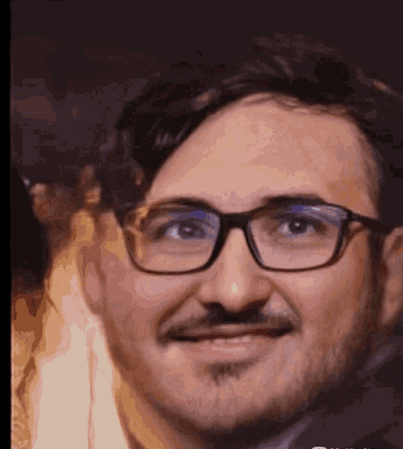 a close up of a man 's face with glasses and a beard