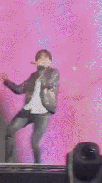 a man is dancing in front of a pink backdrop