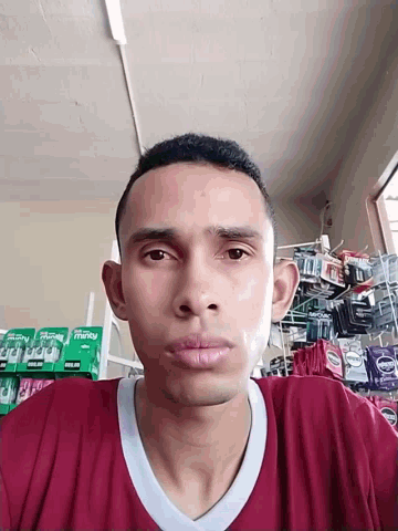 a man in a maroon shirt is standing in front of a shelf with a few packs of mrs. dash