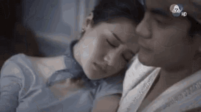 a man and a woman are laying next to each other on a bed with their eyes closed .