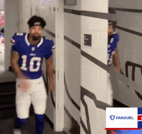 a man in a buffalo bills uniform is walking through a hallway