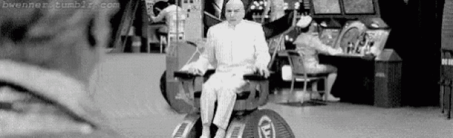 a man is sitting in a wheelchair in front of an arcade machine in a black and white photo .