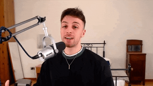 a man is standing in front of a shure microphone in a bedroom