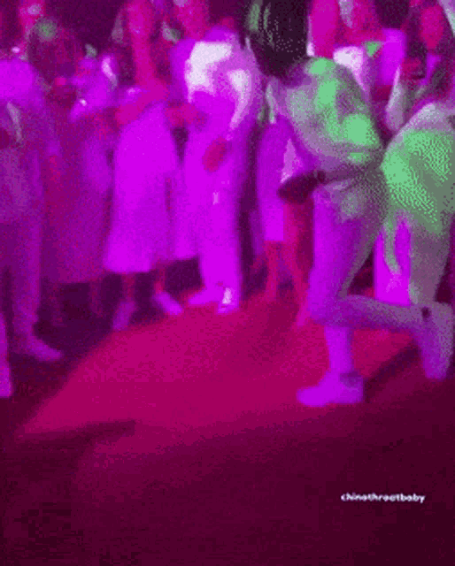 a group of people are dancing in a dark room with purple lights and the words chinathroatbaby on the bottom