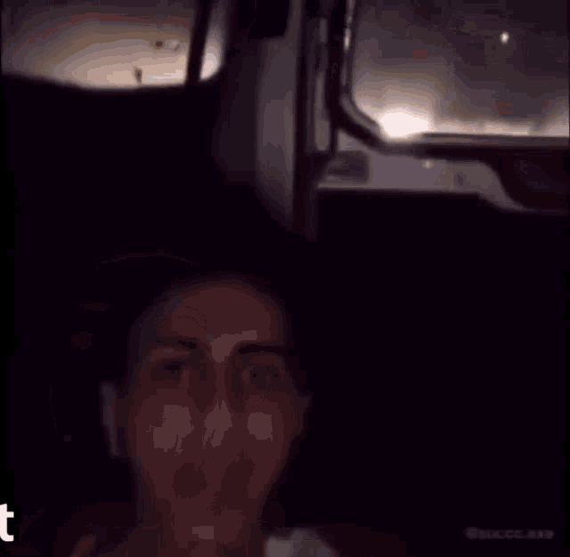 a woman is sitting in a dark room with the word t on the bottom