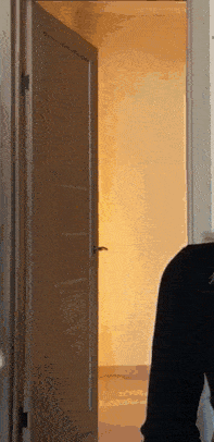 a person is standing in front of a door that is open to a room .