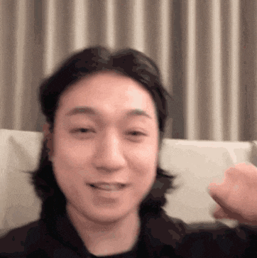 a man with long hair is sitting on a couch and making a face .