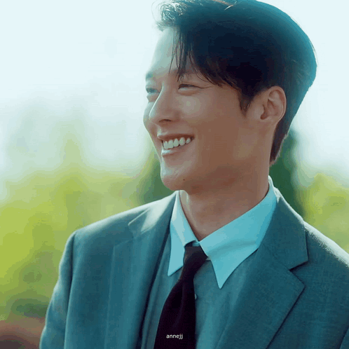 a man in a suit and tie is smiling and the name anneji is on the bottom