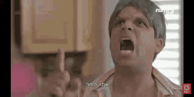 a man is screaming in a kitchen with a foreign language behind him
