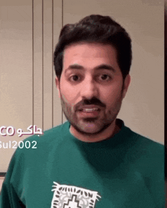 a man with a beard wearing a green sweatshirt is making a funny face .