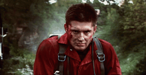 a man with blood on his face is wearing a red shirt with a backpack .