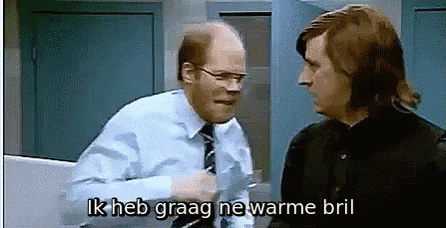 a man in a blue shirt and tie is talking to another man in a black shirt .
