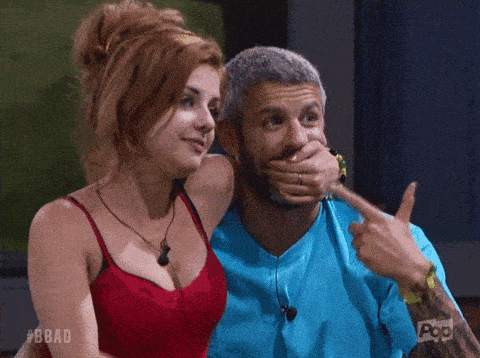 a man is covering his mouth with his hand and a woman is pointing at him