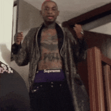 a man with a tattoo on his chest wearing purple supreme underwear