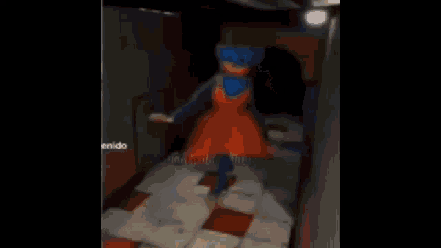 a blue and orange cartoon character is walking down a hallway in a video game .