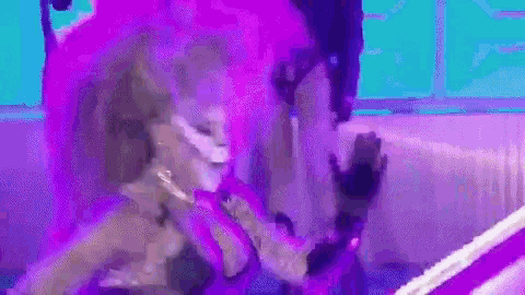 a woman in a purple dress is dancing on a stage with a microphone in her hand .