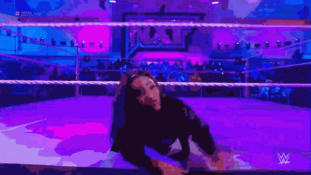 a woman is laying on the ground in a wrestling ring with the letters w on the bottom
