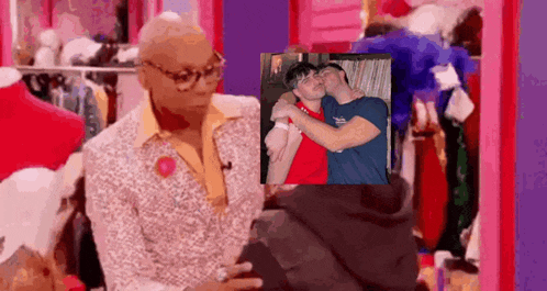 a man in a suit is holding a picture of two men kissing .