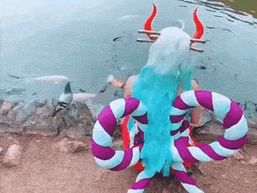 a woman in a costume is sitting next to a lake .