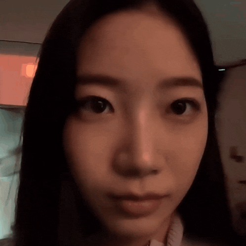 a close up of a woman 's face looking at the camera with a blurry background .