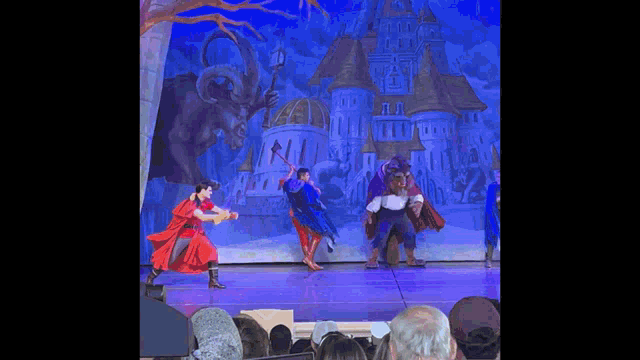 a group of people are dancing on a stage in front of a castle and a monster