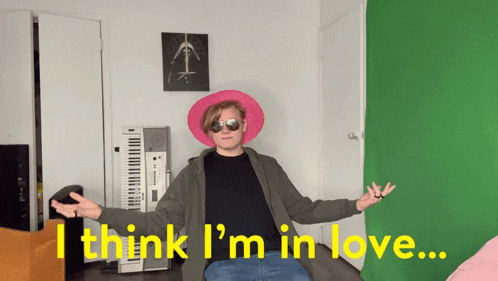 a man wearing sunglasses and a pink hat says i think i 'm in love