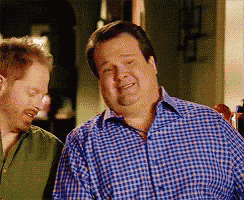 two men are standing next to each other and one is wearing a plaid shirt .