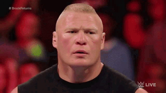 a man in a black shirt is standing in front of a crowd and making a funny face .