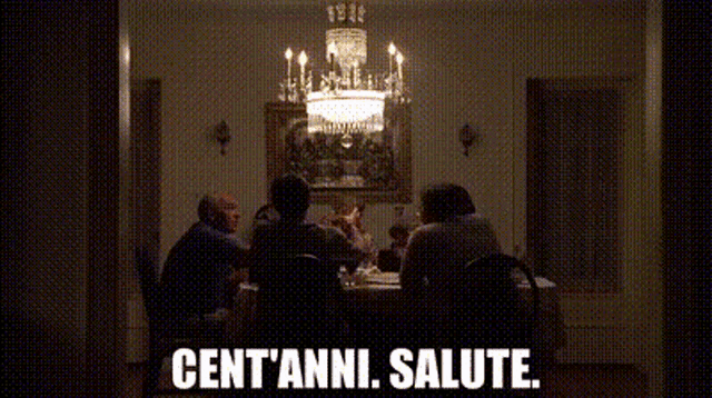 a group of people are sitting at a table with the words cent ' anni salute written in white