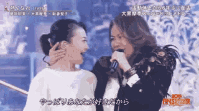 two women singing in front of a microphone with chinese writing