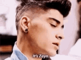 a close up of a young man 's face with the words `` it 's zayn '' written on his neck .