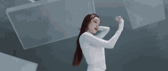 a woman in a white dress is dancing in a room with white lights .